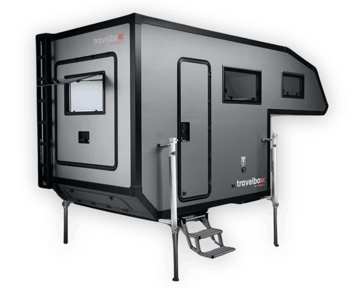 Ein moderner, grauer Pickupboxx-Aufsetzkabine-Camper mit großen Fenstern, Seiteneinstieg, Trittstufen und stabilen Stützbeinen – außen markant gebrandet mit „travelbox“. Dieses Offroad-Camper-Allroundtalent eignet sich perfekt für individuelle Abenteuer und grenzenlose Freiheit unterwegs. Als Custom Camper vereint er Komfort und Flexibilität auf jedem Terrain und bietet Pickup-Besitzern die ideale Lösung, um das Reisen nach eigenen Vorstellungen zu genießen. Travelboxx - Pickup Wohnkabinen