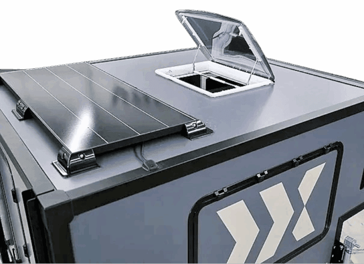 Nahaufnahme eines grauen Fahrzeugdachs mit Solarpanel und geöffnetem Dachlukenfenster – ideal für grenzenlose Freiheit und Unabhängigkeit mit deinem Pickup-Camper. Das markante, geometrische, weiße Design an der Seite unterstreicht die Individualität deines Offroad Campers. Perfekt für alle, die einen maßgeschneiderten Custom Camper als Aufsatz oder Wohnkabine auf ihrem Pickup suchen!. Travelboxx - Pickup Wohnkabinen