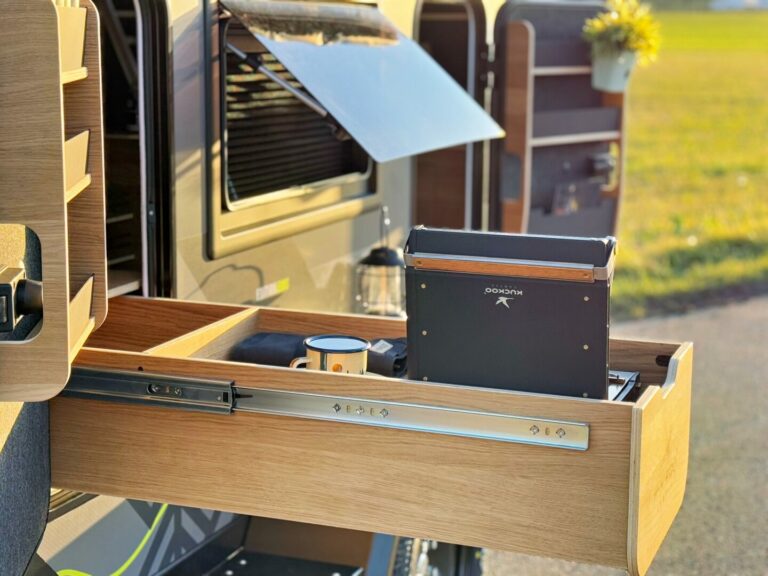 Nahaufnahme einer ausziehbaren Holzküchen-Schublade in einem Pickup Camper mit tragbarem Kocher und Becher – hier wird grenzenlose Freiheit spürbar. Egal ob Offroad-Abenteuer oder spontaner Roadtrip: Dieses Allround-Talent unter den Offroad Campern bietet alles, was du für deine nächste Reise brauchst. Ideal für alle, die auf der Suche nach einem individuell gestalteten Custom Camper sind und Wert auf Flexibilität sowie Unabhängigkeit legen. Perfekt geparkt im Freien bei Sonnenschein – bereit für jedes Abenteuer!. Travelboxx - Pickup Wohnkabinen