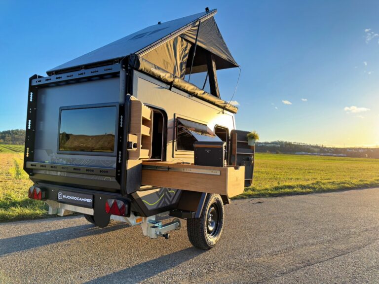 Ein kompakter Offroad-Camper-Trailer, das wahre Allround-Talent, mit erhöhtem Dachzelt steht auf einer Landstraße zwischen weiten Feldern unter klarem, blauen Himmel. Seine seitliche Outdoor-Küche und die geräumigen Staufächer sind geöffnet – bereit für grenzenlose Freiheit und Abenteuer abseits befestigter Wege. Ob als Pickup Camper oder individuell ausgebauter Custom Camper: Dieses Modell bietet flexible Lösungen für alle, die das ultimative Offroad-Erlebnis suchen. Travelboxx - Pickup Wohnkabinen